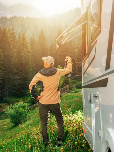 man enjoying the morning sun near an rv in a mountain forest while  national park RV camping in the west